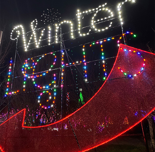 mother and daughter walking through christmas light display
