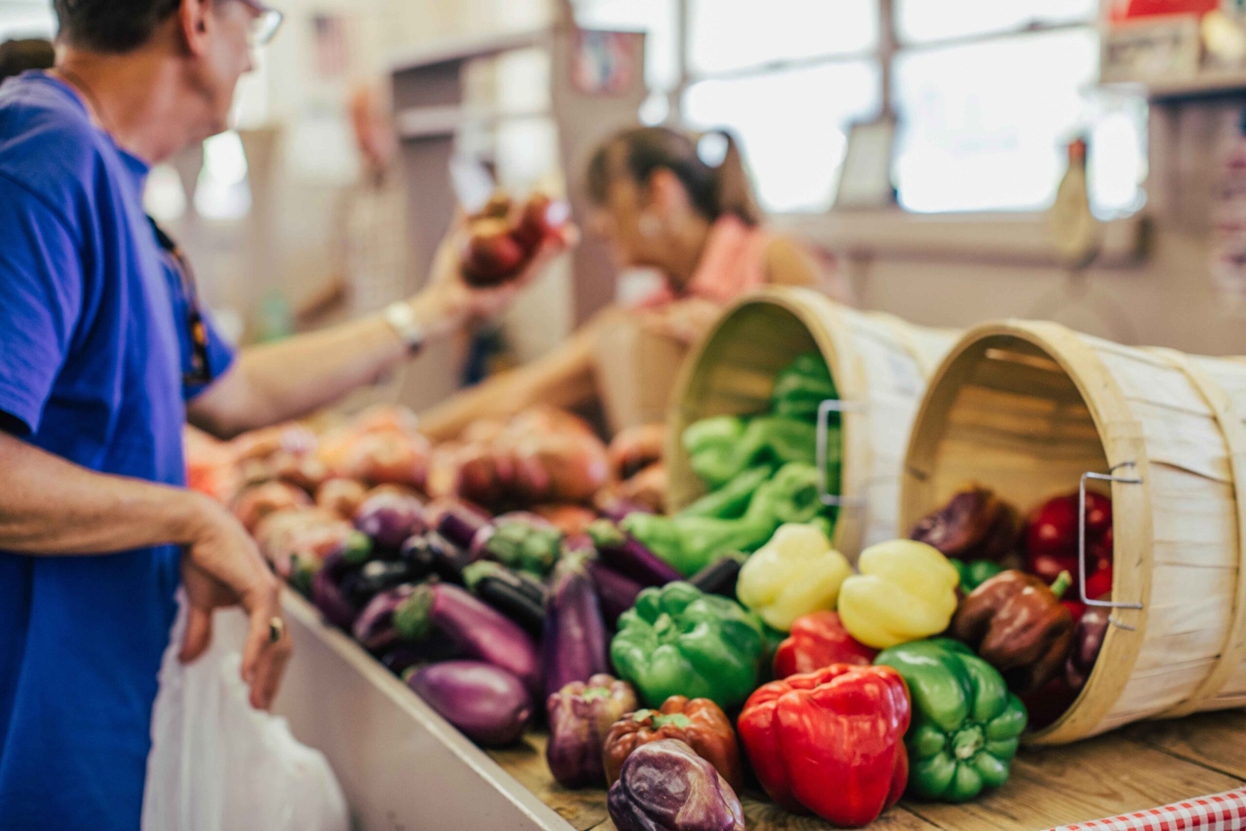 person shopping for produce from wooden baskets at indoor market