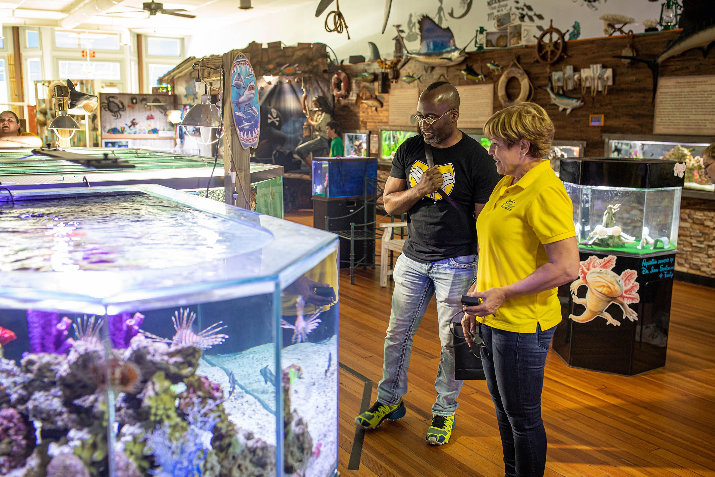people standing next to a large fish tank